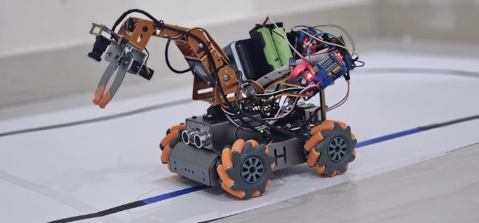 Complex robot with orange wheels and a robotic arm.
